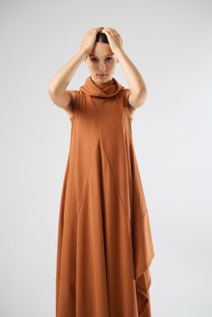 This dress,crafted from high-quality knit fabric,offers a fluid and graceful silhouette that flatters all body types.The sleeveless design is ideal for layering,allowing you to transition effortlessly from season to season.The standout feature of this dress is its unique cowl neckline,adding a touch of contemporary flair to a classic piece.The asymmetrical hemline creates a dynamic visual effect,ensuring you stand out in any crowd.The diagonal seam lines not only enhance the dress's aesthetic appeal but also contribute to its structured fit.Ideal for casual outings or semi-formal events,this terracotta midi dress is versatile enough to be dressed up or down.Pair it with sandals for a relaxed daytime look or with heels and statement jewelry for an evening ensemble. Sleeveless Long Dress, Dress Aesthetic, Dress Crafts, Cowl Neckline, Front Row, Statement Jewelry, Semi Formal, Formal Event, Body Types