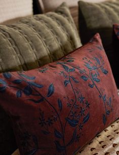 two decorative pillows on a couch in a living room with green velvet upholster