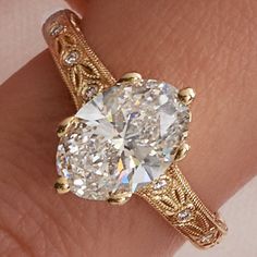 a close up view of a diamond ring on someone's finger, with the center stone surrounded by filigrees