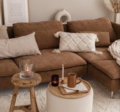 a living room with a brown couch, white rug and candles on the coffee table