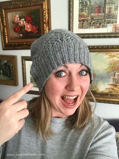 a woman wearing a knitted hat and pointing at the camera with her finger in front of her face