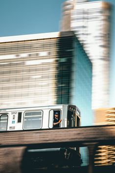 a train traveling over a bridge with tall buildings in the backgroung behind it