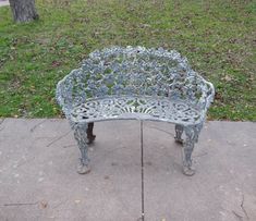 a metal bench sitting on top of a cement slab next to a green grass covered park