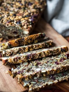 granola bars are stacked on a wooden cutting board