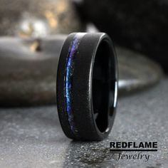 a black ring with blue and purple stars inlayed to it's center