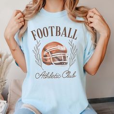 Gear up for game day with our Football Athletic Club Comfort Color Tee. Crafted for comfort and style, this tee is perfect for fans who want to show their support in a laid-back yet spirited way. Emblazoned with the emblem of our Football Athletic Club, this tee exudes team spirit and camaraderie. Whether you're cheering from the stands or watching from home, our tee ensures you'll be representing your team in style. Made from premium materials, this tee offers unparalleled comfort and durabilit Baseball Season Sports Top With Team Logo, Sports Tops With Team Logo For Baseball Season, Sporty Tops For Baseball Season Fan Merchandise, Football Season Game Day T-shirt With Team Name, Team-colored Tops For Baseball Season Fan Merchandise, Game Day T-shirt With Team Name For Football Season, Collegiate T-shirt With Team Logo For Sports Events, Football Season T-shirt With Team Name For Game Day, Football Season Crew Neck Top With Screen Print