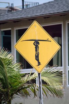 a yellow street sign with a man holding a surfboard on it's back