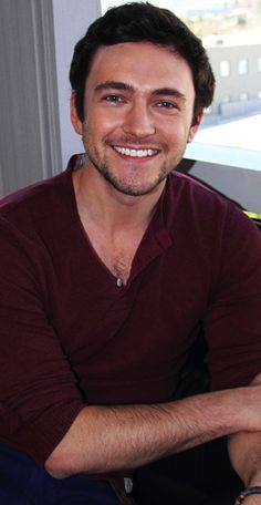 a man sitting in a chair smiling for the camera