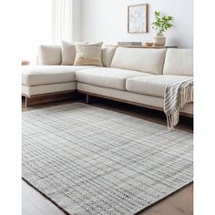 a living room area with a white couch and large rug on the floor next to a window