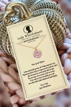 a gold necklace with a pink heart on it and a card that says lady whitteddon's