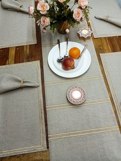 the table is set with place mats, napkins, and fruit on it for an elegant meal