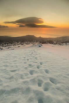 footprints in the snow at sunset on top of a mountain