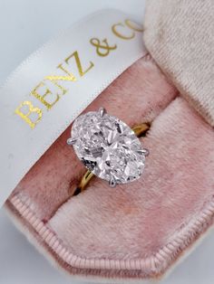 an oval cut diamond sits in a pink velvet box