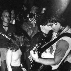 a group of people standing around each other in front of a man holding a guitar