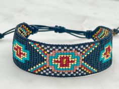 Introducing our southwestern cross cuff bracelet- perfect for adding a touch of boho chic to any outfit! This bracelet is handmade with black leather trim and colorful seed beads, and features an adjustable closure for a perfect fit. It is beaded on strong beading thread & flexible natural leather for comfortable stylish look. It can be worn alone or stacked with other pieces. 7/8 of an inch wide. This bracelet will fit a 6-8 inch wrist. When you purchase this bracelet, I make it to order, just Bohemian Beaded Bracelets With Adjustable Band, Bohemian Multicolor Beaded Bracelets With Adjustable Band, Bohemian Multicolor Beaded Bracelet With Adjustable Band, Adjustable Black Cuff Bracelet With Colorful Beads, Adjustable Multicolor Southwestern Cuff Bracelet, Southwestern Multicolor Adjustable Cuff Bracelet, Adjustable Black Bohemian Beaded Bracelets, Southwestern Black Bracelets For Festival, Southwestern Black Festival Bracelets