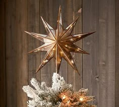 a christmas tree topper is hanging from a wooden fence with snowflakes on it