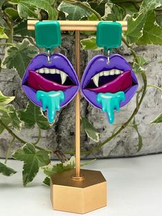 Description: Pastel Goth Vampire Mouth Statement Earrings  These items are individually made with love by me. Details: Handmade item Materials: Acrylic & Resin  Hypo-allergenic stainless steel posts Includes rubber backs Color: Purple & Blue  Length: 2.5" Style: Pastel Goth/ Vampire / Whimsigoth / Cute Emo / Witchy / Kawaii Goth  CARE INSTRUCTIONS: Store out of direct sunlight and keep away from water. it is not recommended to wear these earrings in or around water Handmade Vampire Style Jewelry For Party, Gothic Earrings For Costume Party, Punk Halloween Drop Earrings, Punk Style Halloween Drop Earrings, Gothic Handmade Earrings For Party, Handmade Gothic Earrings For Party, Halloween Punk Style Single Earring, Punk Halloween Party Earrings, Vampire Style Dangle Party Jewelry