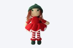 a crocheted doll is wearing a red dress and green hat with white stripes