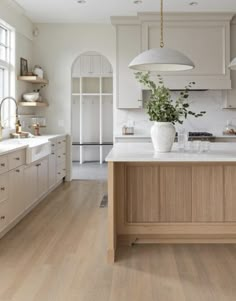 a large kitchen with white cabinets and wood flooring on the countertops, along with an island in the middle