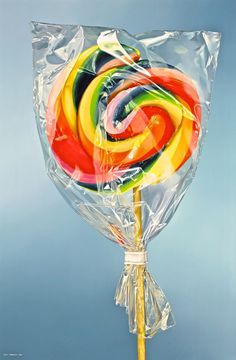 a lollipop is wrapped in clear plastic and sitting on a stick against a blue background