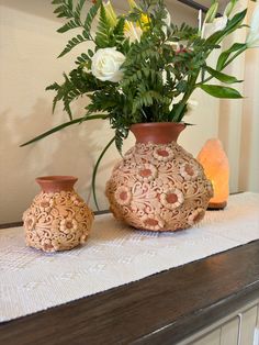 two vases sitting on a table with flowers in them