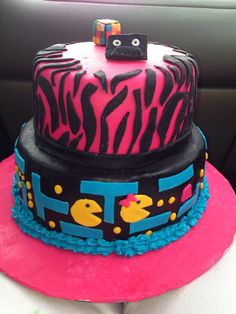 a pink and black zebra print cake on top of a car seat with the number one on it