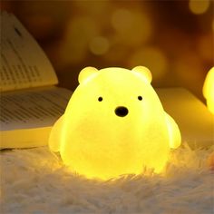 a light that looks like a polar bear is sitting on the floor next to an open book