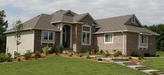 a house with steps leading up to the front door and landscaping on the lawn below