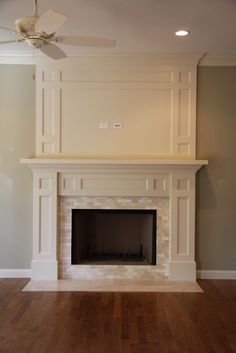 an empty living room with a fireplace and ceiling fan