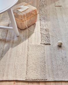 the rug is on the floor next to a table and chair with a basket in front of it