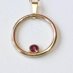 Feel fabulous and loved in this solid 9ct yellow gold and ruby circular pendant.  Named the 'Oriana Rose', meaning Golden Sunrise, this pendant shimmers and shines around your neck, evoking a real festive feel. Symbolising the circle of life in a year, the Oriana Rose is an ideal Mother's Day gift. The ruby is a rich and vibrant red; red being the colour of  love and glints beautifully in its rub over setting. You don't need to worry about buying the correct size; this pendant fits all and has a clip on bail so you can wear it with or without the bail and includes the chain photographed. So why do you need this pendant?  A ring might not be the exact message you want to convey and bracelets are tricky to size as well. This pendant is on trend, but is unique in its design. My silver and gol Yellow Gold Birthstone Necklace With Bezel Setting For Anniversary, Hallmarked Yellow Gold Birthstone Necklace Gift, Yellow Gold Round Jewelry For Valentine's Day, Yellow Gold Anniversary Birthstone Necklace, Anniversary 14k Gold Birthstone Necklace, Red 14k Gold Round Pendant Birthstone Necklace, Red 14k Gold Birthstone Necklace With Round Pendant, Gold Ruby Necklaces With Bezel Setting, Red Birthstone Necklace In 14k Gold