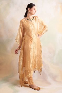 Gold tissue kaftan style kurta with lace trims and tassel hem. Comes with soft modal gold pant.
Component: 2
Pattern: Solid
Neckline: V-Neck
Sleeve Type: Batwing
Fabric: Kurta: Tissue, Pant: Soft Modal
Color: Gold
Other Details: 
Tassel hem
Lace trims
Side slits
Note: Inner worn by the model is not for sale
Occasion: Mehendi and Haldi - Aza Fashions Traditional Kaftan, Kaftan Kurta, Kurta And Pants, Gold Pants, Indian Designers, Kaftan Style, Pants Fabric, Pants Fit, Kurta With Pants