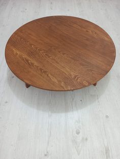 a round wooden table on white wood flooring