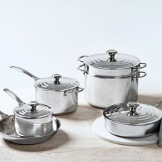 a set of pots and pans sitting on top of a wooden table next to each other