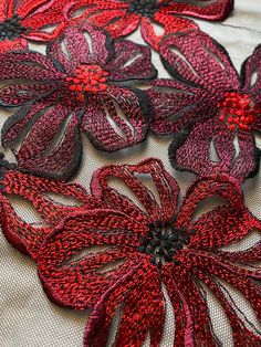 red and black flowers on white fabric with dark center pieces in the shape of petals