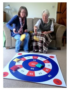 two women sitting on a couch next to a game board with numbers and dices