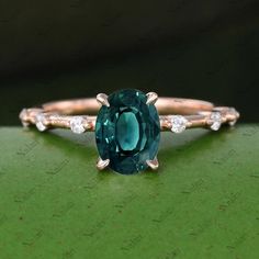 an oval cut green tourmaline and diamond ring on top of a green surface