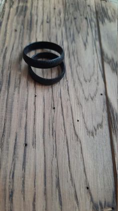 two black bracelets sitting on top of a wooden table