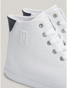 Tommy Hilfiger men's sneaker. Hit the streets running with these casual lace-up sneakers, emboldened by a high-top leather construction and our TH monogram embossed on the side.  Material: 100% Leather (fwa). High-top Sneakers With Embossed Logo For Streetwear, Classic High-top Sneakers With Embossed Logo, Sporty Leather High-top Sneakers With Embossed Logo, Mid-top Leather Sneakers With Embossed Logo, Classic Lace-up High-top Sneakers With Perforations, Classic High-top Sneakers With Perforated Toe Box, White Leather Tommy Hilfiger Sneakers, Casual High-top Sneakers With Embossed Logo, Tommy Hilfiger High-top Sneakers For Streetwear