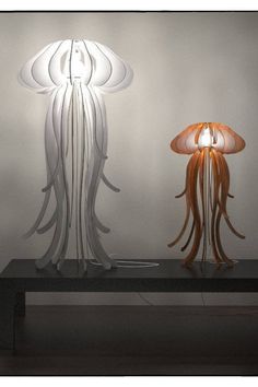 two lamps that are sitting on top of a table next to each other in front of a white wall