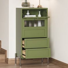 a green cabinet with three drawers and two lamps on the top shelf next to it