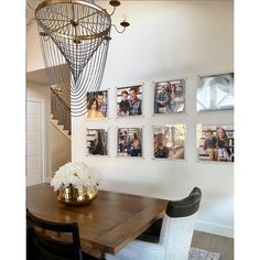 a dining room table with chairs and pictures on the wall above it, along with flowers