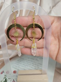 Our Clear Quartz Sun Gold Handmade Earrings are a stunning addition to any jewelry collection. These earrings are beautifully crafted by hand using high-quality materials and feature a gorgeous clear quartz crystal . The earrings are lightweight, making them comfortable to wear all day long. They are the perfect accessory for any occasion, whether you're dressing up for a special event or adding a touch of sparkle to your everyday outfit. Our Clear Quartz Sun Gold Handmade Earrings are not just Celestial Gold Round Earrings, Gold Celestial Round Earrings, Celestial Drop Earrings Gift, Celestial Round Crystal Earrings For Gift, Celestial Style Drop Earrings As Gift, Celestial Round Crystal Earrings As Gift, Celestial Single Earring Jewelry Gift, Celestial Single Earring Jewelry For Gift, Gold Crescent Spiritual Earrings