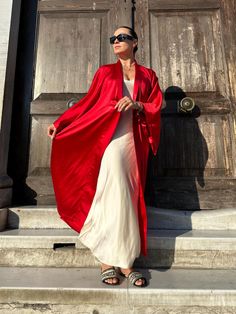 This red kimono robe is a stunning piece that combines elegance and comfort, making it a perfect addition to any wardrobe. Made from luxurious satin, this kimono robe offers a silky, smooth texture that feels exquisite against the skin. As a long kimono robe, it provides full coverage, ensuring both modesty and a touch of drama with its flowing silhouette. The long sleeves add to its sophisticated look, making it a standout piece for kimono homewear. This kimono dress can easily transition from Elegant Floor-length Satin Kimono, Elegant Kimono As A Gift, Elegant Kimono With Kimono Sleeves As A Gift, Elegant Kimono With Kimono Sleeves For Gift, Elegant Long Silk Kimono, Elegant Red Wrap Kimono, Elegant Open Front Satin Kimono, Elegant Satin Open Front Kimono, Silk Maxi Length Kimono