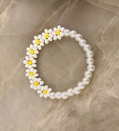 two bracelets with white and yellow flowers on them sitting on top of a rock