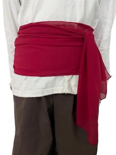 the back of a person wearing a white shirt and brown pants with a red sash