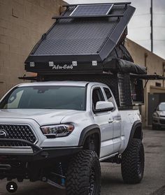 a white truck parked in front of a building with a solar panel on it's roof