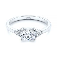 a white gold engagement ring with an oval cut diamond and side stones on the band