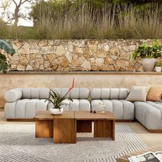 a living room filled with lots of furniture next to a stone wall covered in plants