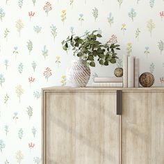 a wooden cabinet topped with a potted plant next to a wallpapered wall